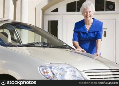 Senior woman standing with her car outside her home