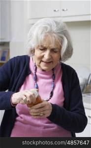 Senior Woman Struggling To Take Lid Off Jar