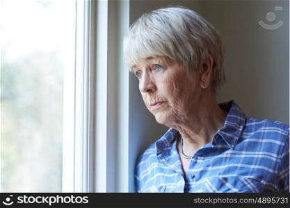 Senior Woman Suffering From Depression Looking Out Of Window