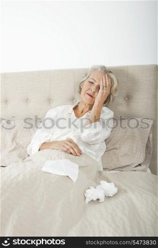 Senior woman suffering from headache resting in bed
