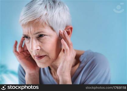 Senior woman suffering from tinnitus or ringing in her ears.. Senior Woman Suffering From Tinnitus