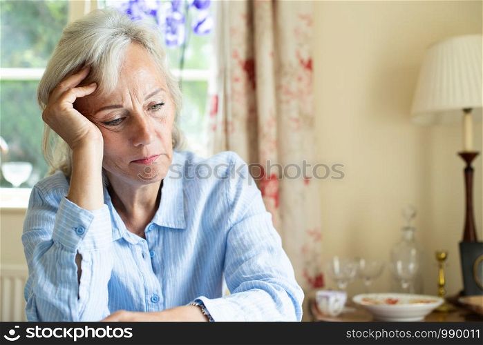 Senior Woman Suffering With Depression With Head In Hands At Home