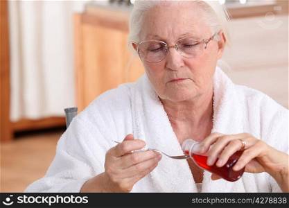 Senior woman taking cough syrup