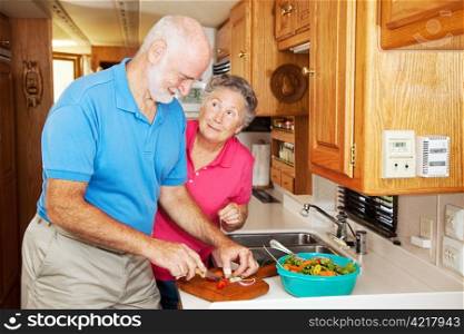 Senior woman thanking her husband for helping prepare dinner in their RV kitchen.