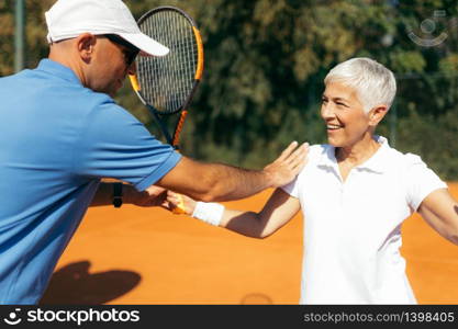 Senior Woman Training with Tennis Instructor on a Clay Court