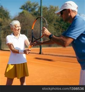 Senior Woman Training with Tennis Instructor on a Clay Court