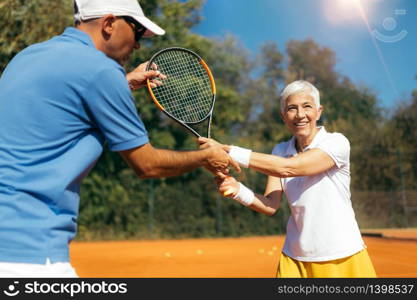 Senior Woman Training with Tennis Instructor on a Clay Court
