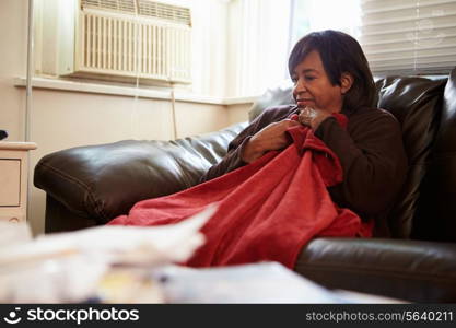 Senior Woman Trying To Keep Warm Under Blanket At Home