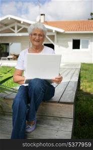 Senior woman using a laptop outside her house