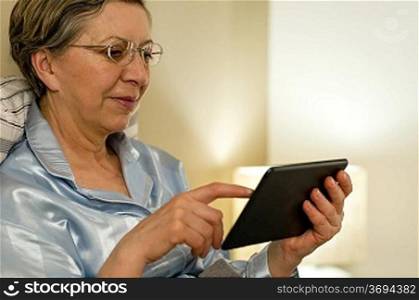 Senior woman using digital tablet lying in bed