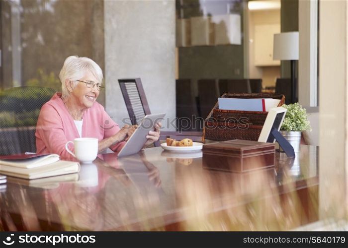 Senior Woman Using Digital Tablet Through Window