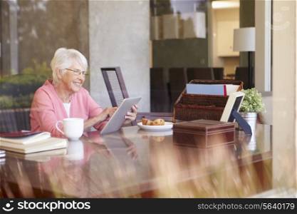 Senior Woman Using Digital Tablet Through Window