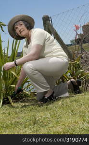 Senior woman using hedge clippers in a garden