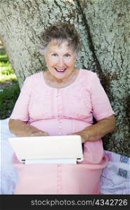 Senior woman using her netbook computer outdoors on a wireless network.