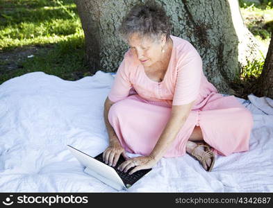 Senior woman using her netbook laptop computer outdoors.