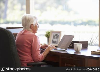 Senior Woman Using Laptop On Desk At Home