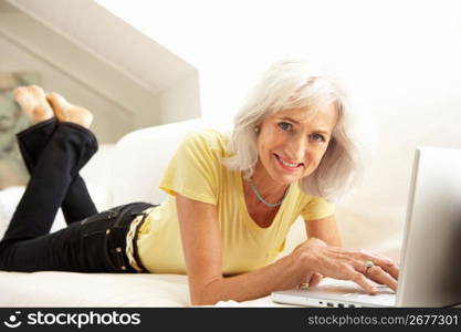 Senior Woman Using Laptop Relaxing Sitting On Sofa At Home