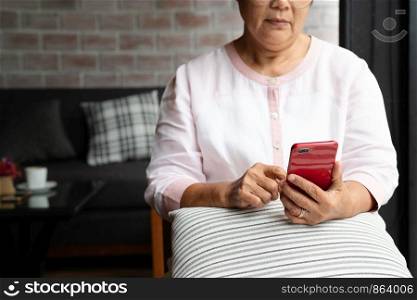 senior woman using mobile phone white sitting on sofa at home