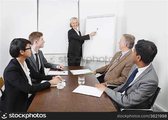 Senior woman using whiteboard in business meeting