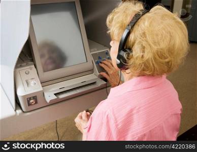 Senior woman voting in braille on a touch screen machine for vision impaired.