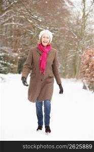 Senior Woman Walking Through Snowy Woodland