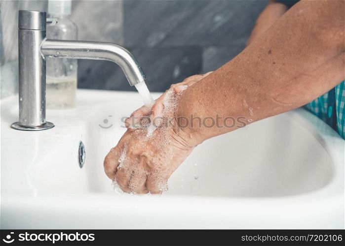 Senior woman wash hand for prevention of novel Coronavirus Disease 2019 or COVID-19 . People wash hands at bathroom sink to clean the virus infection.