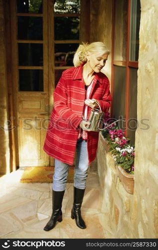 Senior woman watering plants with watering can and smiling