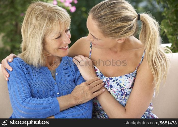 Senior Woman With Adult Daughter Relaxing On Sofa At Home