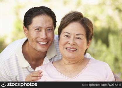 Senior Woman With Adult Son In Garden