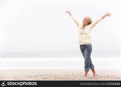 Senior Woman With Arms Outstretched On Winter Beach