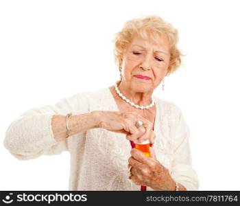 Senior woman with arthritis struggles to open a bottle of prescription medication.