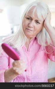 Senior Woman With Brush Concerned About Hair Loss