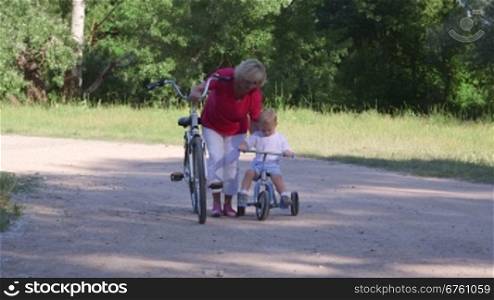 Senior woman with child learning to ride bicycle in the park
