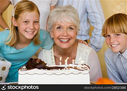 Senior woman with family blowing candles on birthday cake