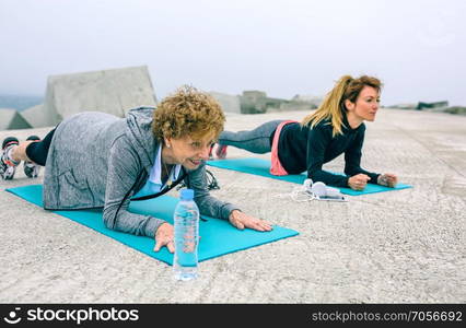 Senior woman with female coach doing plank exercise. Senior woman and coach doing plank exercise