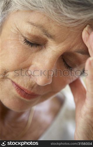 Senior Woman With Head In Hands Looking Weary