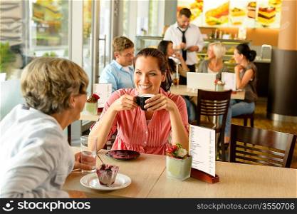 Senior woman with her daughter at cafe drinking eating happy