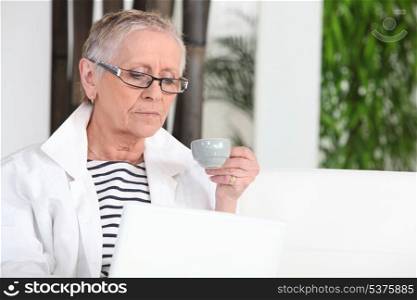 Senior woman with laptop computer drinking coffee