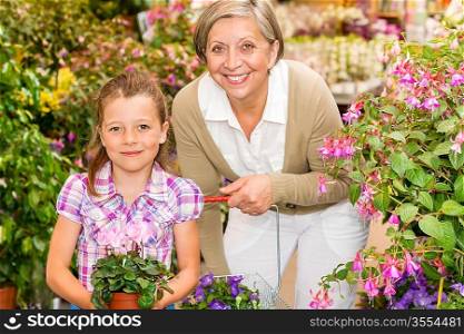 Senior woman with little girl shopping flowers at garden centre