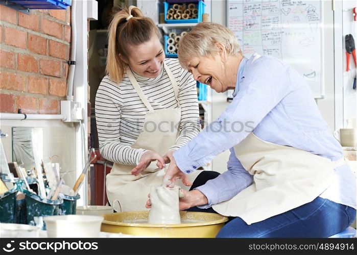 Senior Woman With Teacher In Pottery Class