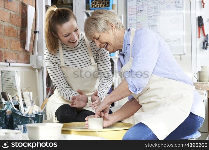 Senior Woman With Teacher In Pottery Class