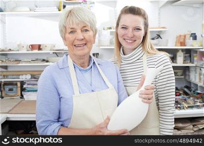 Senior Woman With Teacher Looking At Vase In Pottery Class