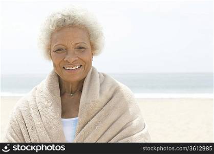 Senior woman with towel round her shoulders on beach