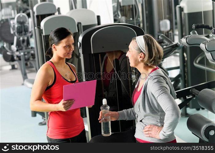 Senior woman with trainer discuss personal plan at gym