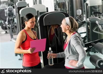 Senior woman with trainer discuss personal plan at gym