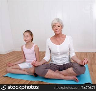 Senior woman with young girl doing yoga exercises