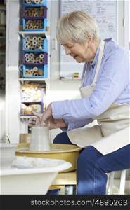 Senior Woman Working At Pottery Wheel In Studio
