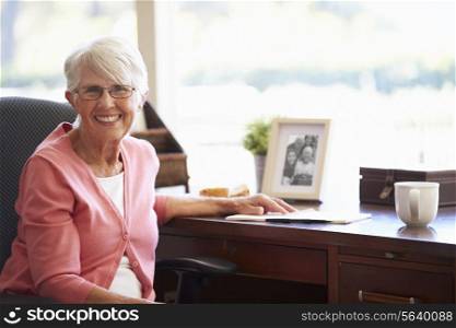 Senior Woman Writing Memoirs In Book At Desk