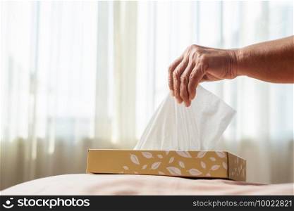 Senior women hand picking napkin/tissue paper from the tissue box