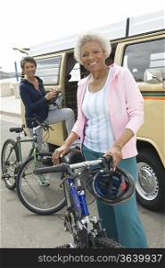 Senior women stand beside campervan with mountain bikes